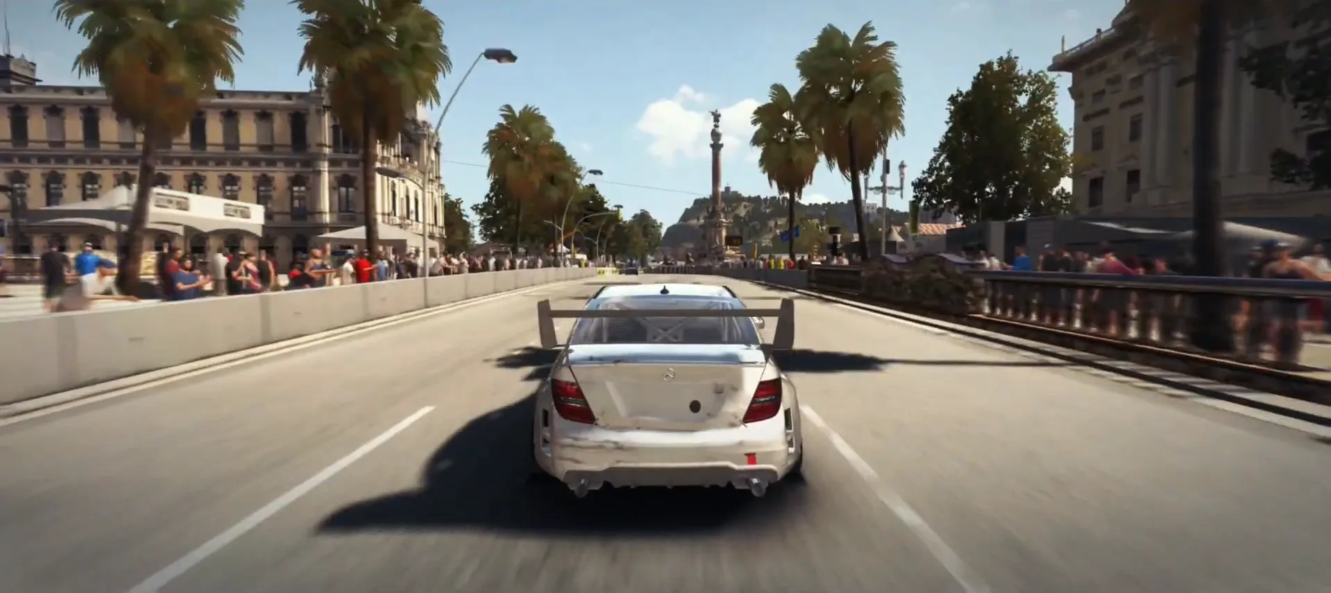 A white touring car chasing down a street circuit lined with palm trees and packed grandstands in Grid Autosport