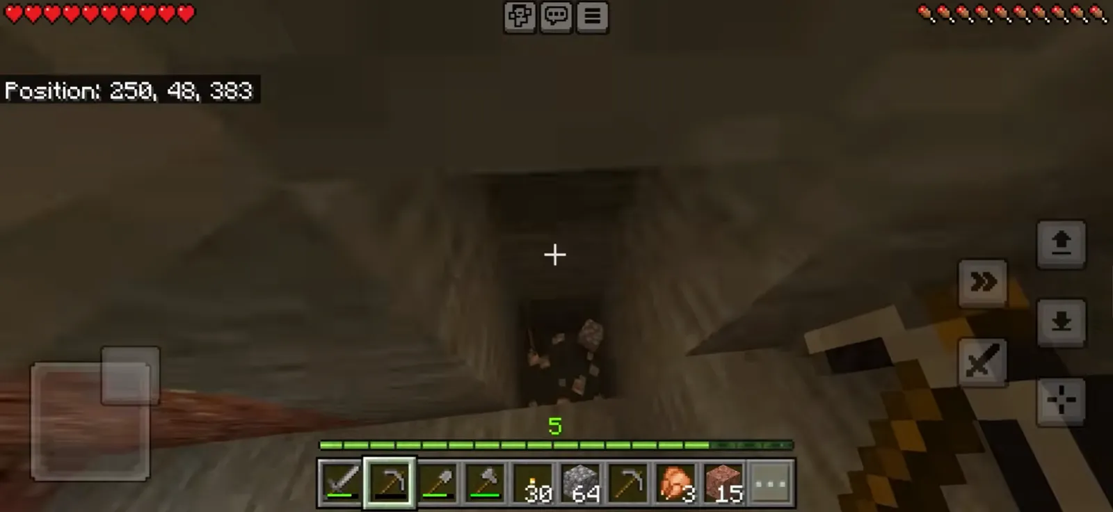 Minecraft underground in first person, a torch-lit tunnel ahead and a pickaxe selected in the hotbar