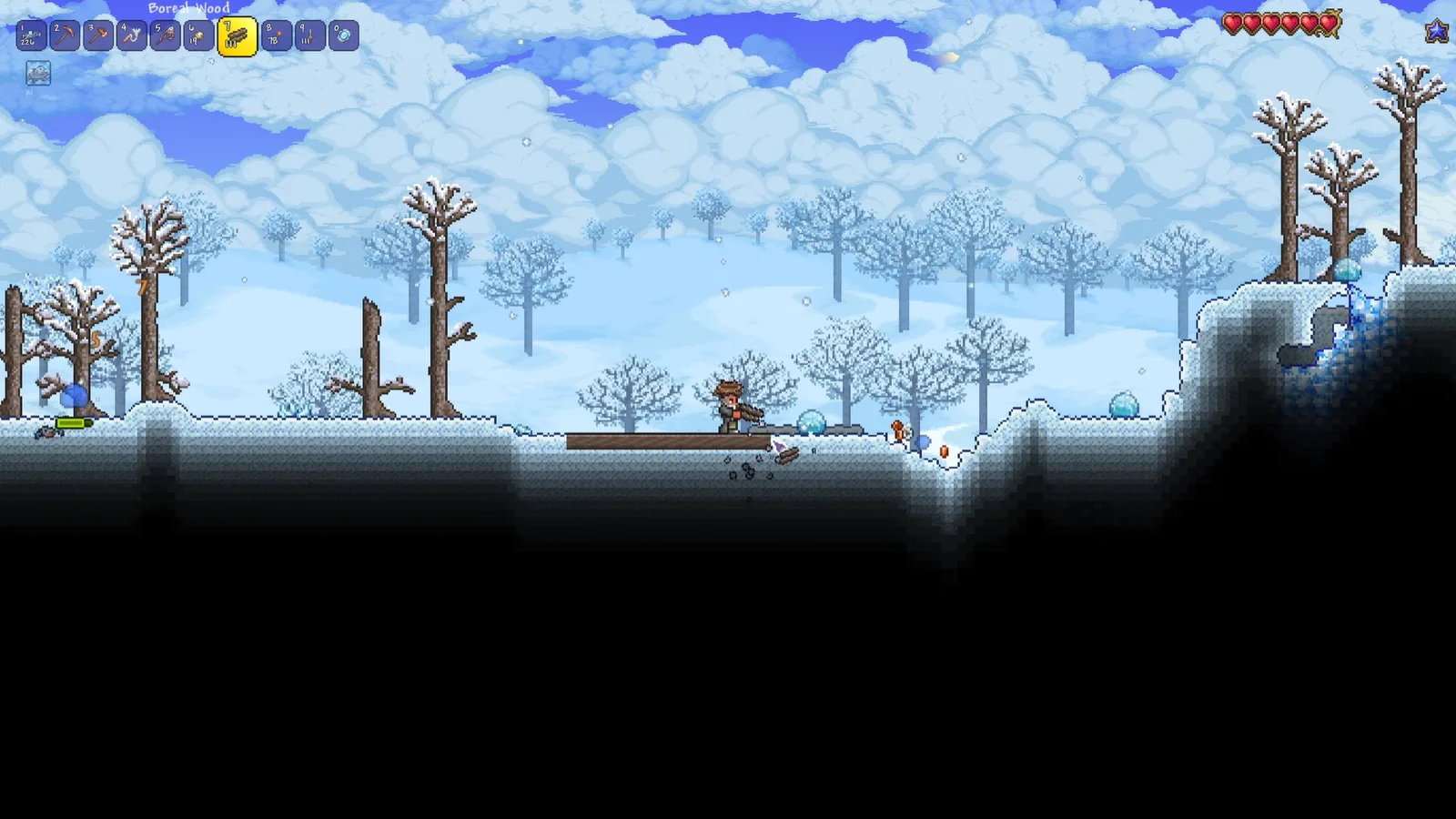 A Terraria snow biome, the player chopping boreal wood on a bare hilltop under falling snow